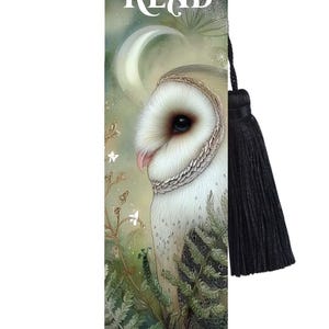 May include: A bookmark with a detailed illustration of a white owl and a black tassel. The bookmark has the text "Let me READ IN PEACE". The background shows a moonlit scene. The bookmark is a reading accessory.