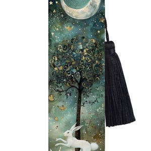 May include: A black bookmark featuring a white rabbit leaping from a tree, with a crescent moon and stars in the background. The bookmark has a black tassel.