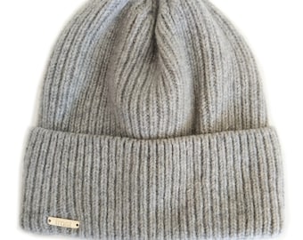 May include: Gray knitted beanie with a ribbed texture and a small gold label that says "frost" on the front.