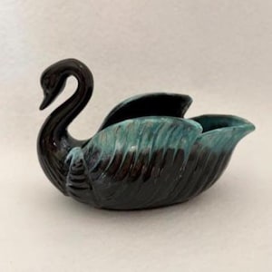 May include: A ceramic swan-shaped bowl featuring a glossy dark brown finish on the neck and base, with textured wing details highlighted by a vibrant teal glaze along the upper edges and feathers, creating a distinct two-tone color effect.