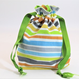 May include: A colorful striped drawstring bag with green ribbon ties. The bag is made of fabric and has a light yellow, orange, blue, gray, and green striped pattern.