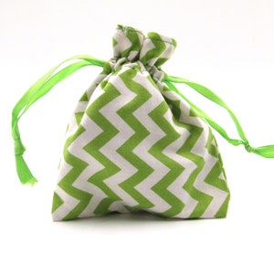 May include: A small, drawstring gift bag with a white and green chevron pattern. The bag is tied with bright green satin ribbon. The bag is likely made of fabric and is suitable for small gifts or trinkets.