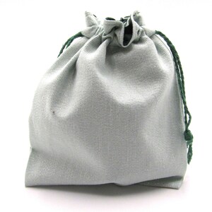 May include: A light gray drawstring bag with a green drawstring. The bag is made of a soft, textured fabric.
