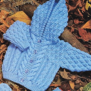 May include: A light blue knitted baby cardigan with a hood, button fastening, and cable knit design.
