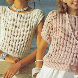 Könnte beinhalten: Zwei Frauen tragen gehäkelte Oberteile. Das Oberteil links ist weiß und das Oberteil rechts ist rosa. Beide Oberteile haben eine lockere, offene Maschenstruktur.