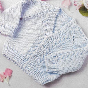 May include: A light blue knitted baby cardigan with a cable knit pattern and button closures.
