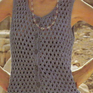 May include: A sleeveless crocheted vest with a button-up front. The vest is made with a light grey yarn and has a delicate openwork pattern.