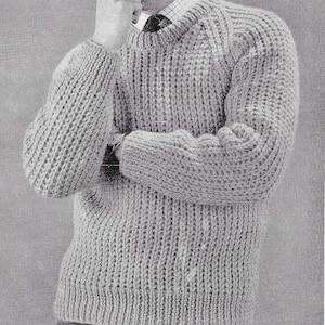 Puede incluir: Un suéter gris de punto con cuello redondo y mangas largas. El suéter tiene una textura acanalada.