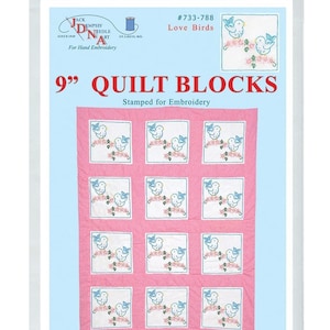 Puede incluir: Un paquete de 12 bloques de colcha pre-estampados de 23 cm x 23 cm con un fondo rosa y un cuadrado blanco en el centro. Cada cuadrado tiene un diseño de dos pájaros azules en una rama con flores rosas. El paquete está etiquetado como "9" Quilt Blocks" y "Love Birds".