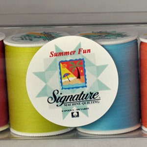 Peut inclure: Un ensemble de huit bobines de fil de différentes couleurs, dont rose, turquoise, magenta, jaune, bleu, orange, marron et violet. Les bobines sont étiquetées "Summer Fun" et "Signature" avec une étoile et une scène de plage.
