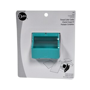 May include: A turquoise blue thread cutter caddy with a clear plastic window. The caddy is labeled "Thread Cutter Caddy" and has the words "Chariot Coupe-Fil" and "Portador Cortahilos" printed on the packaging.