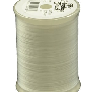 May include: A spool of white thread with the text "The Finishing Touch" and "Best-In-Class" printed on the label. The label also includes the text "XC5957" and "1200 yds".