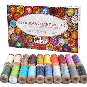 May include: A set of 20 small spools of 100% cotton embroidery floss in various colors. The spools are wooden and have a label with the brand name "Aurifil" and the text "Glorious Handwork by Liza Lucy and Kim McLean".