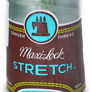 Peut inclure: Une bobine de fil à coudre Maxi-Lock Stretch de couleur vert clair. L'étiquette indique "Maxi-Lock Stretch" en lettres blanches sur fond brun. L'étiquette indique également "Soft, Like Yarn" et "Textured Nylon".