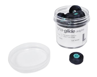 Może przedstawiać: Przezroczysty plastikowy słoik wypełniony szpulkami granatowej nici, oznaczony jako "magna-glide delights". Obok słoika znajduje się pojedyncza szpulka i przezroczysta pokrywka. Tekst na etykiecie brzmi "The perfect match to Glide top thread."