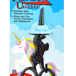 Pode incluir: Tesoura Unicórnio Arco-íris, um par de tesouras pequenas em forma de unicórnio com acabamento arco-íris. As tesouras medem 10 cm de comprimento e são embaladas em um cartão azul e branco com o texto "Scissors Rainbow Unicorn" e "Try me".