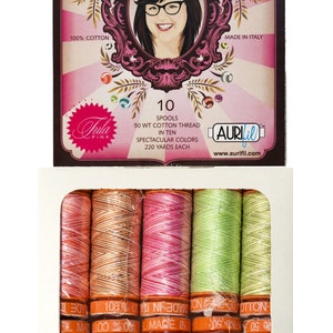 Peut inclure: Une boîte de 10 bobines de fil à coudre en coton de 50 poids en dix couleurs. Chaque bobine contient 220 yards de fil. La boîte est étiquetée "Premium Cotton Thread" et "Aurifil".
