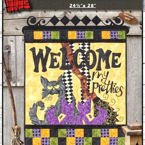 May include: A quilted wall hanging titled Welcome My Pretties measuring 24.5 inches by 28 inches. The design features a black cat, a broomstick, and purple witch boots on a yellow background with a black, green, and orange checkered border.