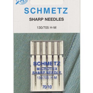 Puede incluir: Un paquete de 6 agujas de coser Schmetz Microtex Sharp de tamaño 70/10, etiquetadas como 130/705 H-M. Las agujas están en una caja de plástico transparente con una etiqueta azul y blanca.