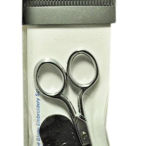May include: A silver 4-inch curved blade embroidery scissors with a black leather sheath. The scissors are packaged in a clear plastic bag with a black and white label that reads "gingher a tradition of quality".