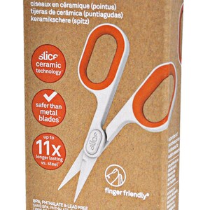 May include: A brown cardboard box with a white label that says "ceramic scissors pointed" and features a picture of a pair of orange and white ceramic scissors. The label also says "slice ceramic technology" and "safer than metal blades".