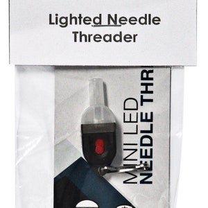 May include: A white and black package containing a small, black, battery-powered LED needle threader. The threader has a red button and a clear plastic tip. The package includes the text "MINI LED NEEDLE THR" and "BRIGHT WHITE LED BATTERIES INCLUDED".
