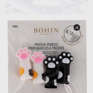 May include: A set of four Bohin France knitting needle point protectors shaped like cat paws. Two protectors are white with orange and black spots and pink paw pads, and two are black with white spots and white paw pads, packaged in plastic.