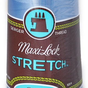 Peut inclure: Une bobine de fil à coudre sergé Maxi-Lock Stretch bleu. La bobine est étiquetée "Soft, Like Yarn" et "Textured Nylon". Elle mesure 1828 mètres de long.