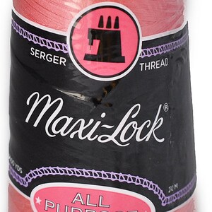 以下が含まれることがあります： ピンクのMaxi-Lockオールパーパス スパンポリエステル サーжер糸の糸巻き。糸巻きにはブランド名と糸の種類が記載されています。