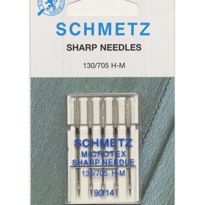 Puede incluir: Un paquete de 5 agujas de coser Schmetz Microtex afiladas, tamaño 130/705 H-M, 90/14. Las agujas están en una caja de plástico transparente con una etiqueta azul y blanca.