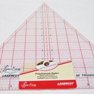 Può includere: Un righello triangolare trasparente per patchwork con linee rosse a griglia e misure. Il righello ha un'etichetta che recita "Patchwork Ruler" e "60 Triangle". Il marchio "Sew Easy" è visibile.