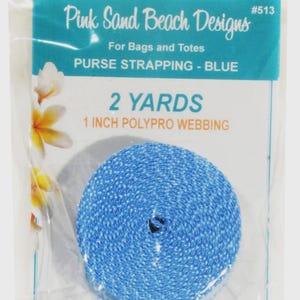 May include: A roll of blue polypro webbing for bags and totes, labeled Pink Sand Beach Designs #513. The packaging states 2 yards and 1 inch polypro webbing. The blue webbing is coiled in a clear plastic bag with a white and teal header card.