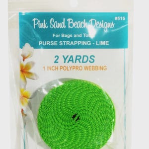 May include: A coil of lime green 1 inch wide polypro webbing in a clear plastic package labeled Pink Sand Beach Designs #515. The packaging indicates 2 yards of purse strapping with a floral graphic on the left side of the label.