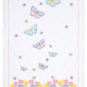 Puede incluir: Tela blanca acolchada con un diseño de mariposas y tulipanes coloridos. Las mariposas vuelan hacia arriba en diagonal, con mariposas más pequeñas dispersas a su alrededor. Los tulipanes están en la parte inferior de la tela, en una fila.