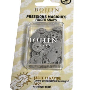 May include: A package of Bohin France finger snaps, a sewing notion. The package features a clear plastic container filled with gray snaps. Text on the package reads "PRESSIONS MAGIQUES FINGER SNAPS" and "EASY As a finger snap!"
