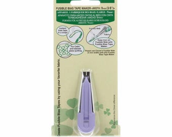 May include: A Clover fusible bias tape maker, width 9mm (3/8"). The package is green and white with text in multiple languages. The tool is purple and designed to create bias tape from fabric. Includes instructions for use.