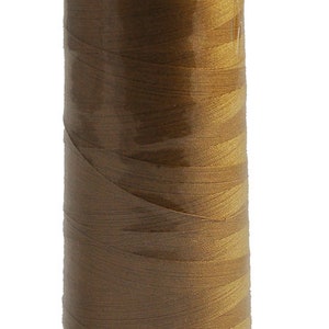 Op de afbeelding: Een spoel goudbruin garen met de merknaam "MADERA" erop gedrukt. De draad is strak gewikkeld rond een witte plastic basis. De spoel is verpakt in doorzichtig plastic.
