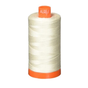 Puede incluir: Una bobina de hilo de color crema con una etiqueta naranja que dice "Aurifil".