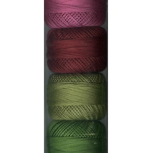 Puede incluir: Un conjunto de seis carretes de hilo de bordar en tonos de rosa, rojo y verde. Los carretes están dispuestos verticalmente en una bolsa de plástico transparente.