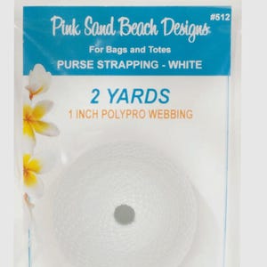 May include: A roll of white 1 inch polypro webbing for bags and totes, labeled Pink Sand Beach Designs #512, containing 2 yards of material. The packaging features a blue header with white text and a floral graphic on the left side.