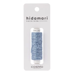 May include: A spool of light blue thread with a silver shimmer, labeled "hidamari SASHIKO&" and "COSMIO" on the packaging.