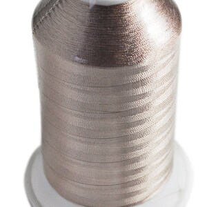 May include: A spool of beige embroidery thread with a label that reads "RHEINGOLD Made in Germany Nr. 40 1500m Viscose Art. 2 V001 Col. 495 142 Lot. 844"