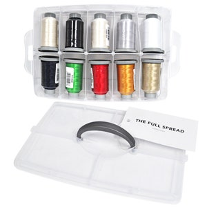 Puede incluir: Una caja de almacenamiento de plástico transparente con asa, que contiene 10 carretes de hilo de varios colores. La caja tiene una etiqueta que dice "THE FULL SPREAD Collection".