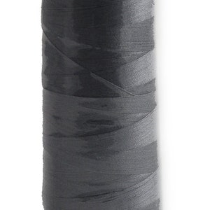 May include: A spool of grey thread with a white label that reads "8111 MADER".
