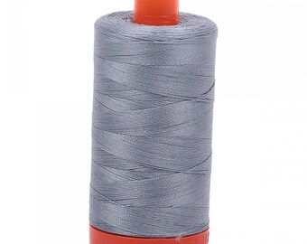 Puede incluir: Una bobina de hilo gris con una bobina de plástico naranja.