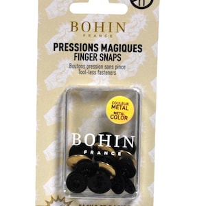 May include: Package of Bohin France finger snaps. The package is light tan with black and gold text. The product is in a clear plastic container. The finger snaps are black with gold metal tops. Text on the package says "Easy as a finger snap!"