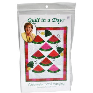 Pode incluir: Padrão Quilt in a Day para uma parede de melancia pendurada. O padrão apresenta um fundo branco com fatias de melancia vermelhas e verdes e videiras verdes. O padrão foi projetado por Patricia Knoechel.