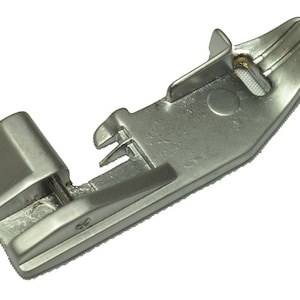 May include: A silver sewing machine foot with a small metal lever on the side.