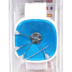 Op de afbeelding: Een witte en blauwe magnetische speldenhouder in een transparante plastic behuizing. De houder heeft een blauw vierkant met een zilveren magneet in het midden en vijf zilveren spelden met witte koppen. De behuizing heeft de tekst "Magnetic Pin Caddy" en het Hemline-logo met de tekst "Quality Checked".