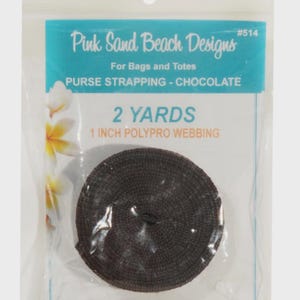 May include: A coil of chocolate brown 1 inch polypro webbing for bags and totes, packaged in a clear plastic bag labeled Pink Sand Beach Designs #514, containing 2 yards of strapping material with a white floral graphic on the left side.